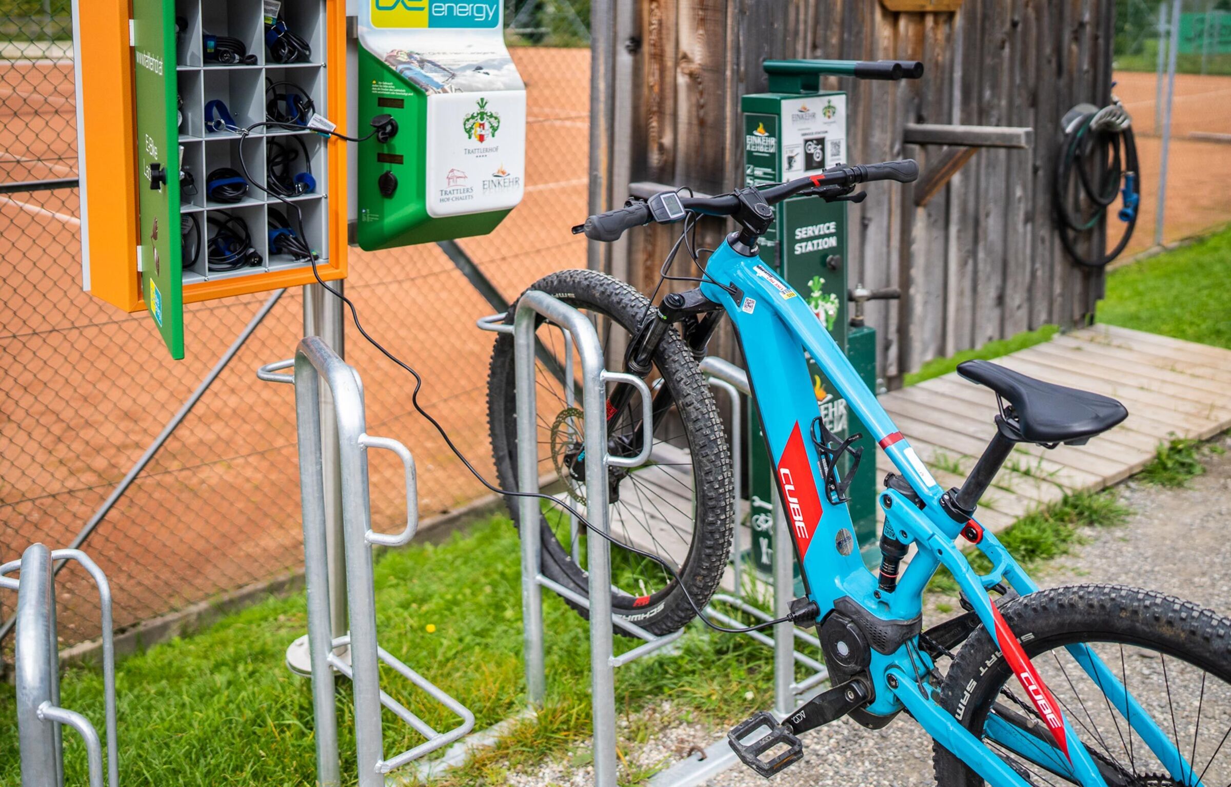 Una e-mountain bike blu a forma di cubo è in carica sulla stazione di ricarica.