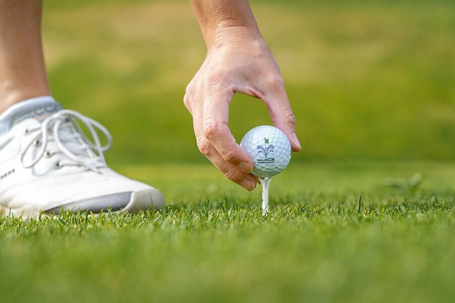A person placing a golf ball on a golf tee
