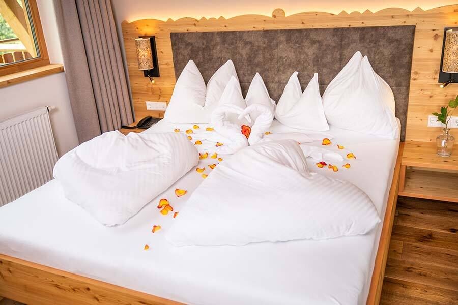 Das Hotelzimmer im Hotel GUT Trattlerhof in Kärnten würde romantisch geschmückt, mit Blütenblätter, herzförmige Bettdecken und Handtuch-Schwan