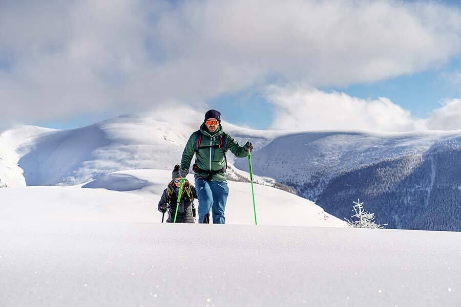 Due persone che camminano con le racchette da neve nella neve alta.