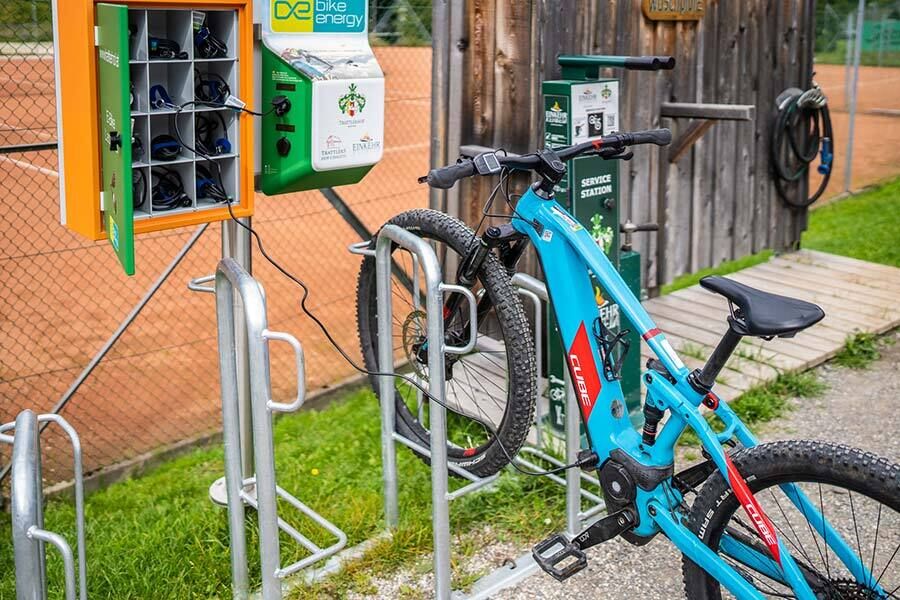 Una e-mountain bike blu a forma di cubo è in carica sulla stazione di ricarica.