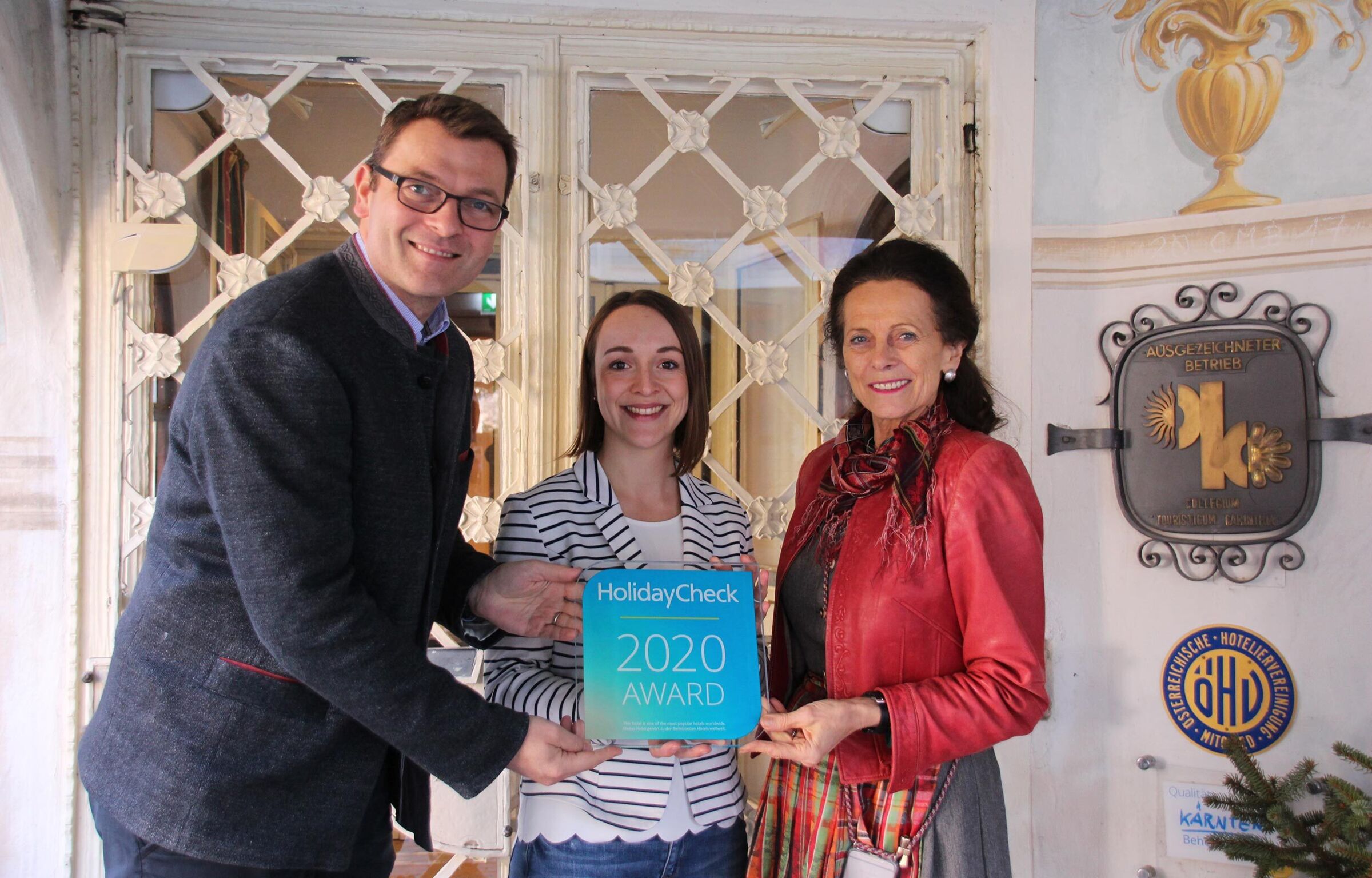 3 persone tengono in mano un premio Holiday Check 2020.