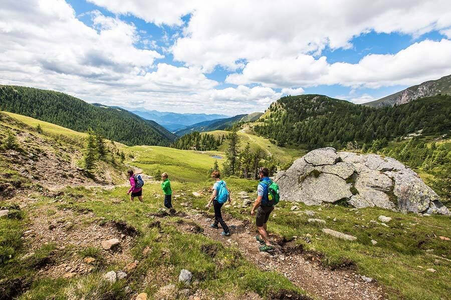 Eine vierköpfige Familie geht bei schönem Wetter auf den Nockbergen wandern