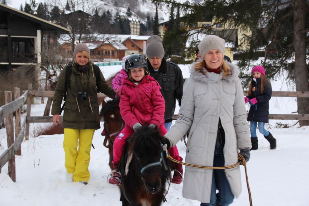 Children and adults on the pony farm in winter at the hotel trattlerhof