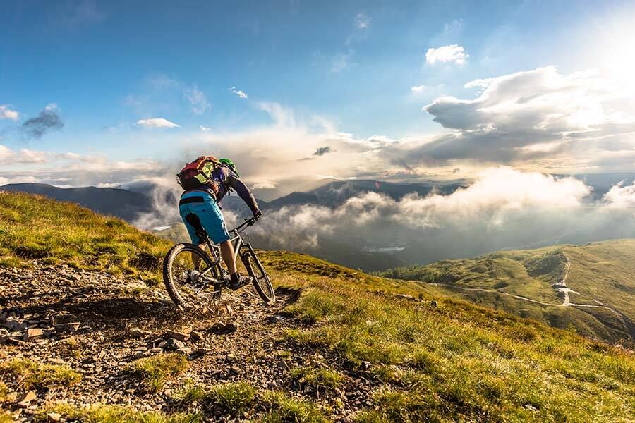 A cyclist is about to ride his mountain bike down a hill.