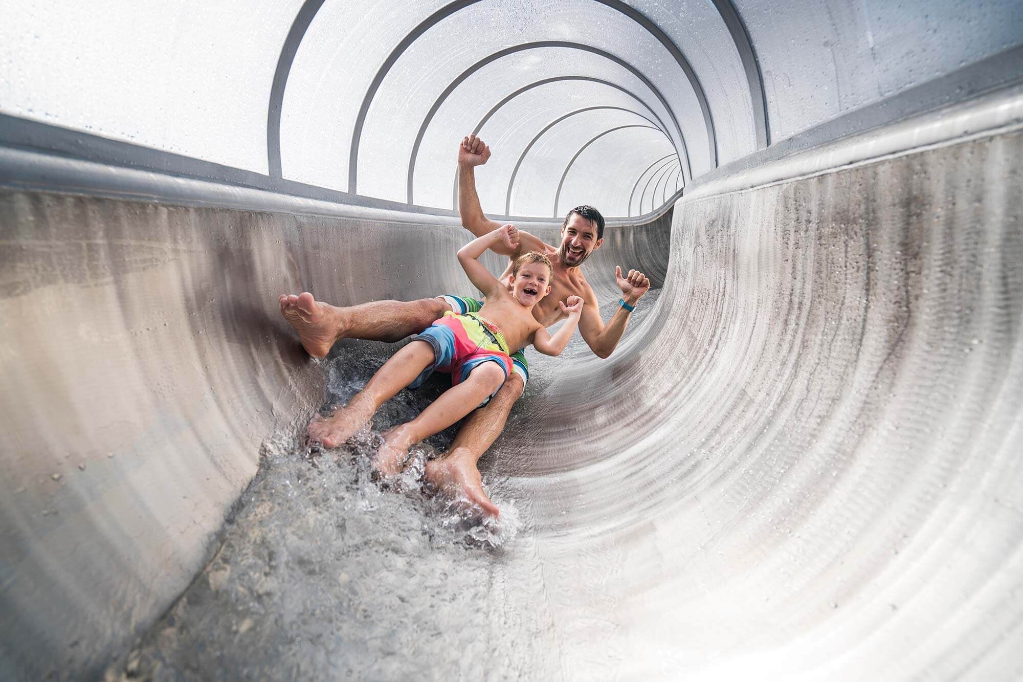 A father sliding down a slide at the Familientherme st. Kathrein together with his son.