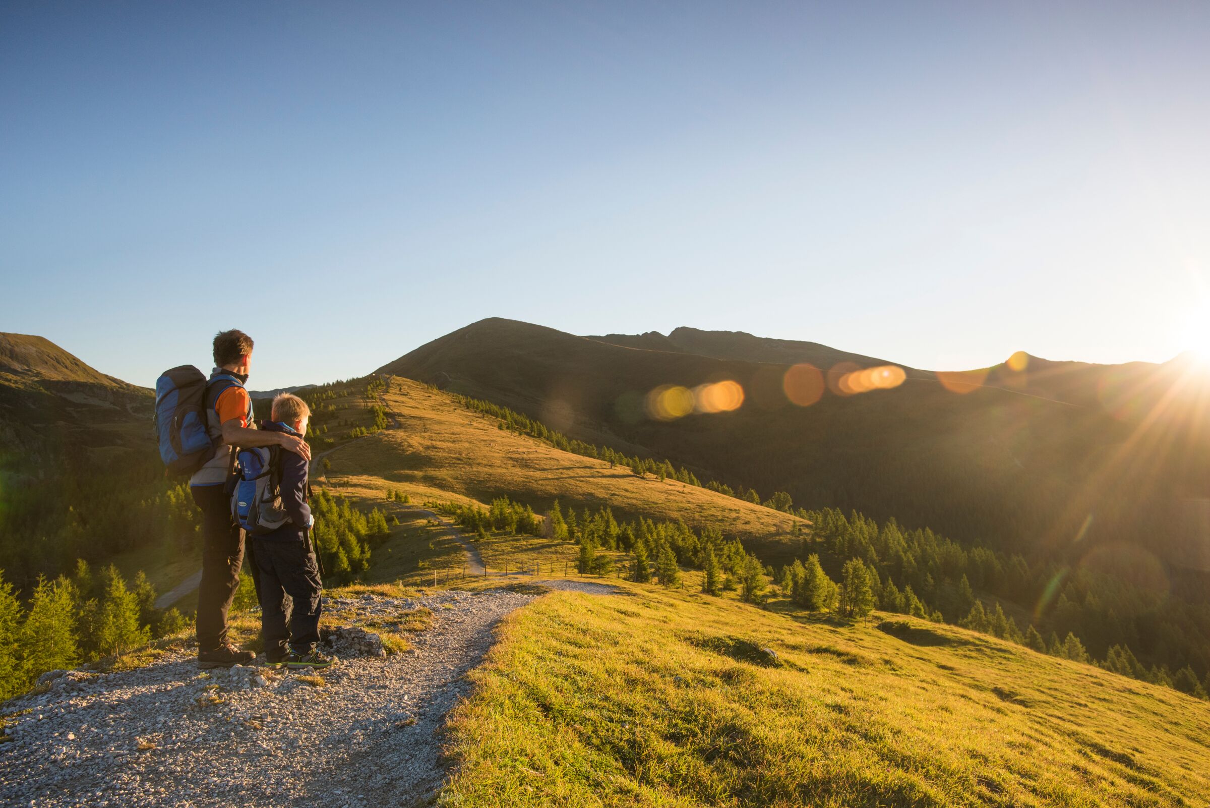 Father and son walking in the beautiful mountains and looking at the sun.