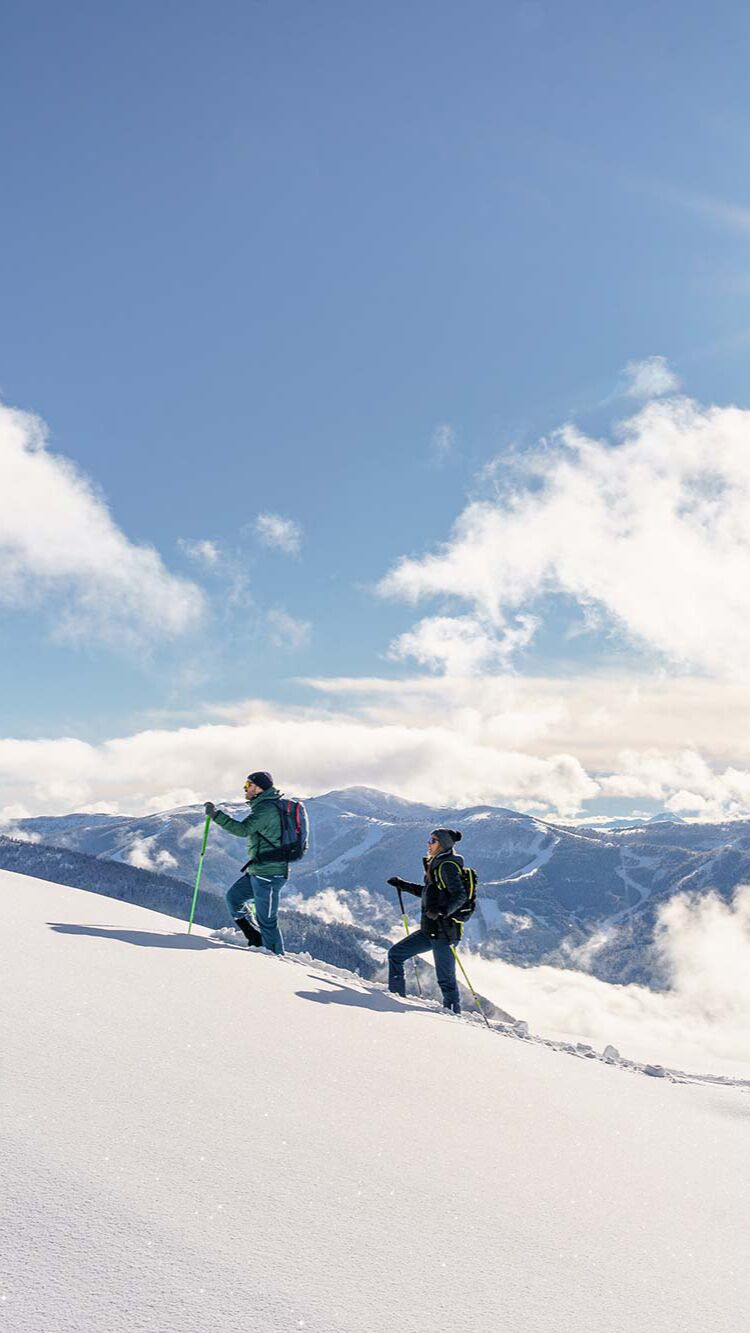 Due persone che ciaspolano nella neve alta in Carinzia.