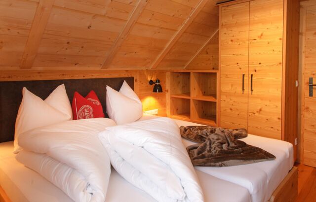 Ein Doppelbett befindet sich in einem Chalet-Zimmer aus Holz