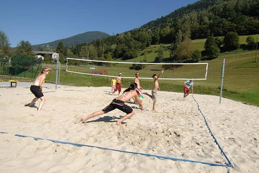 Eine Gruppe von Jugendlichen spielen am Beachvolleyballplatz vom Hotel GUT Trattlerhof**** in Bad Kleinkirchheim Volleyball