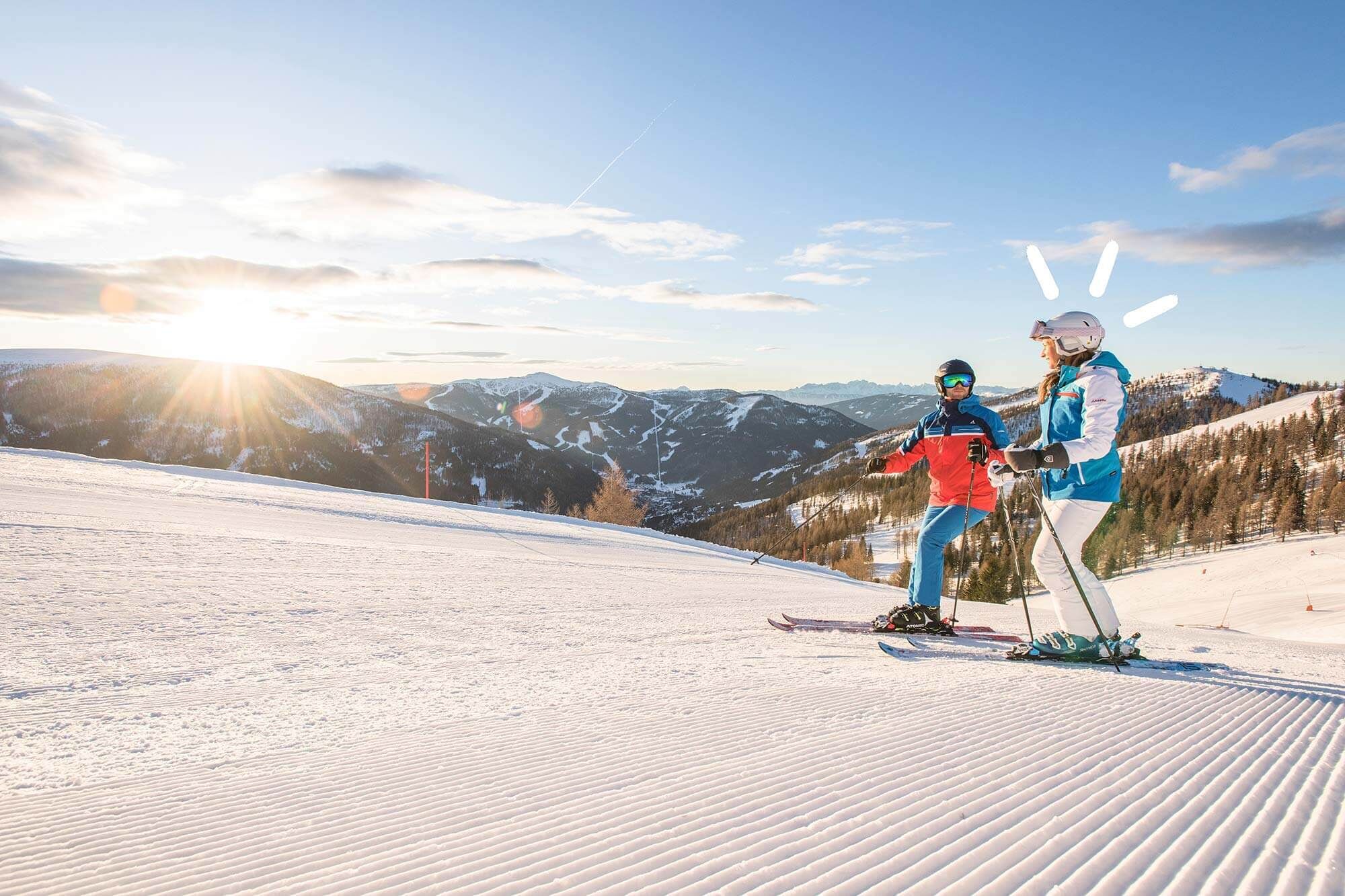 Two people skiing on a freshly groomed slope with a beautiful mountain backdrop.