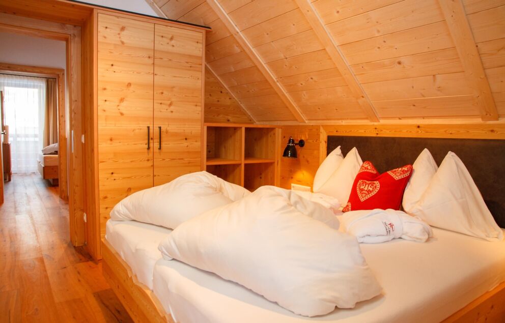 Ein Doppelbett befindet sich in einem Chalet-Zimmer aus Holz