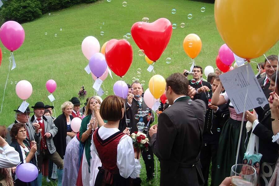 Die Hochzeitsgäste in Tracht lassen bei der Hochzeit in Kärnten Luftballone und Seifenblasen steigen