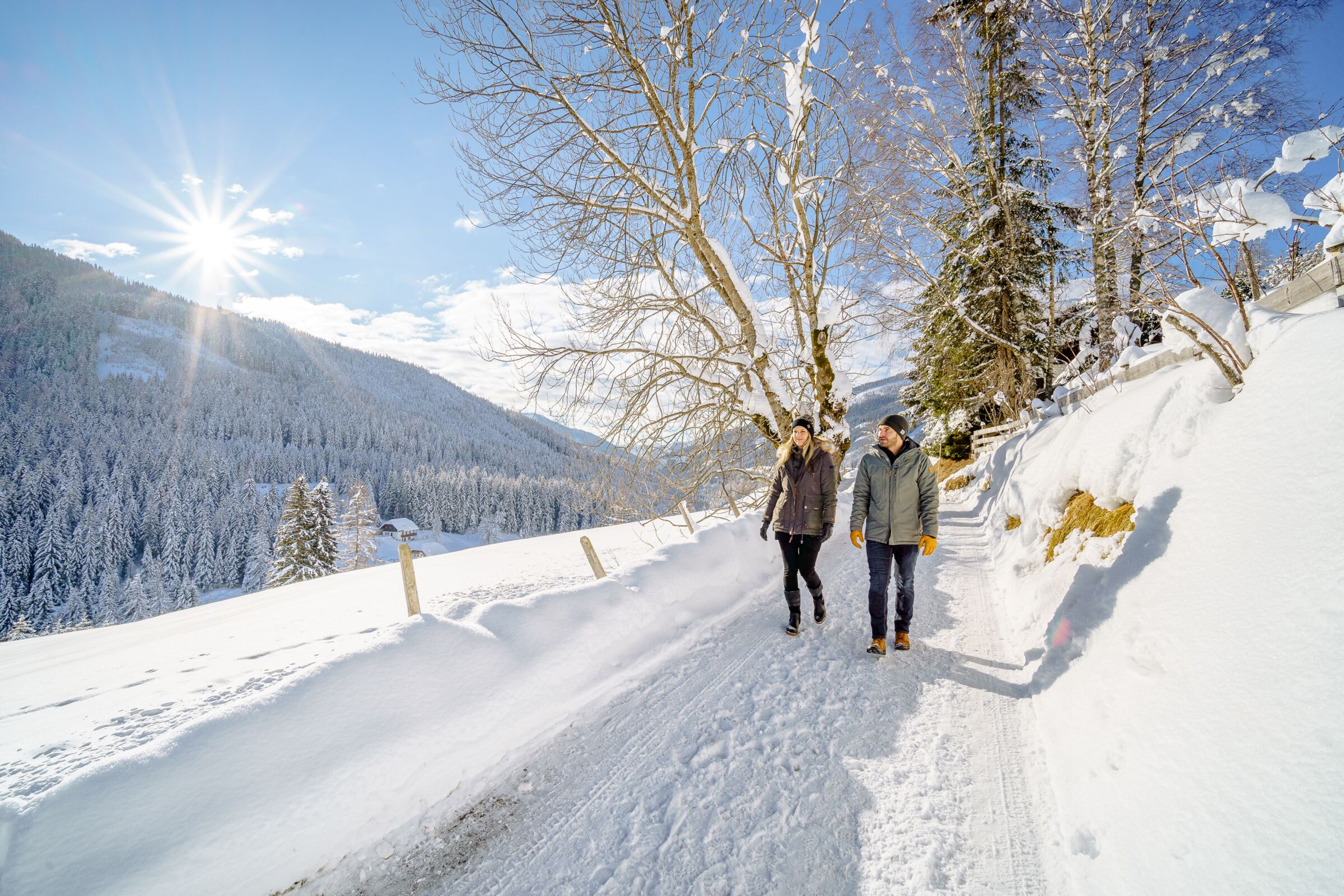Una coppia che fa una passeggiata invernale a Bad Kleinkirchen nella natura innevata.