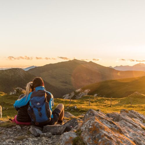 A couple watches the sunrise while hiking in Carinthia