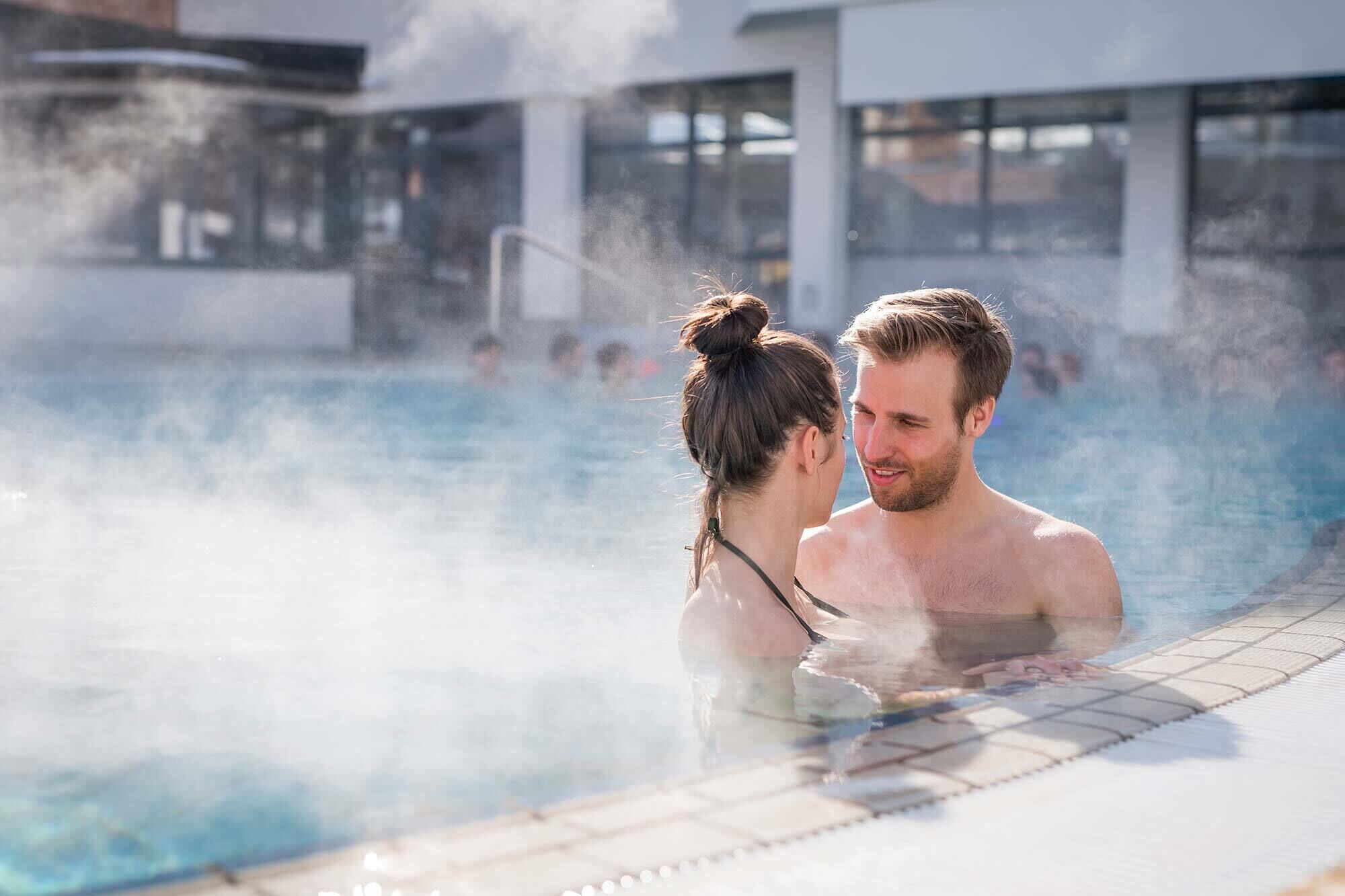 Coppia in piedi in piscina che si guarda romanticamente.