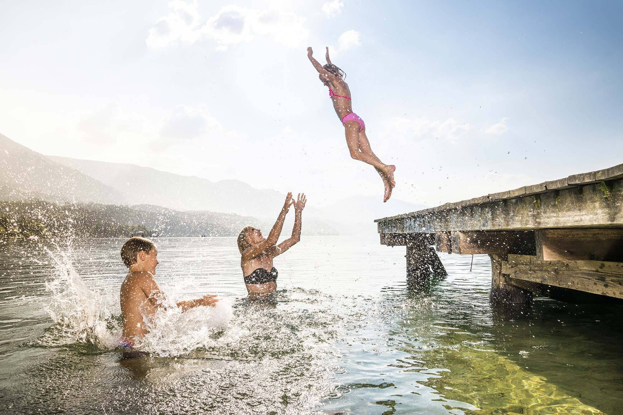 La bambina salta da un pontile nel lago dove la madre vuole prenderla.