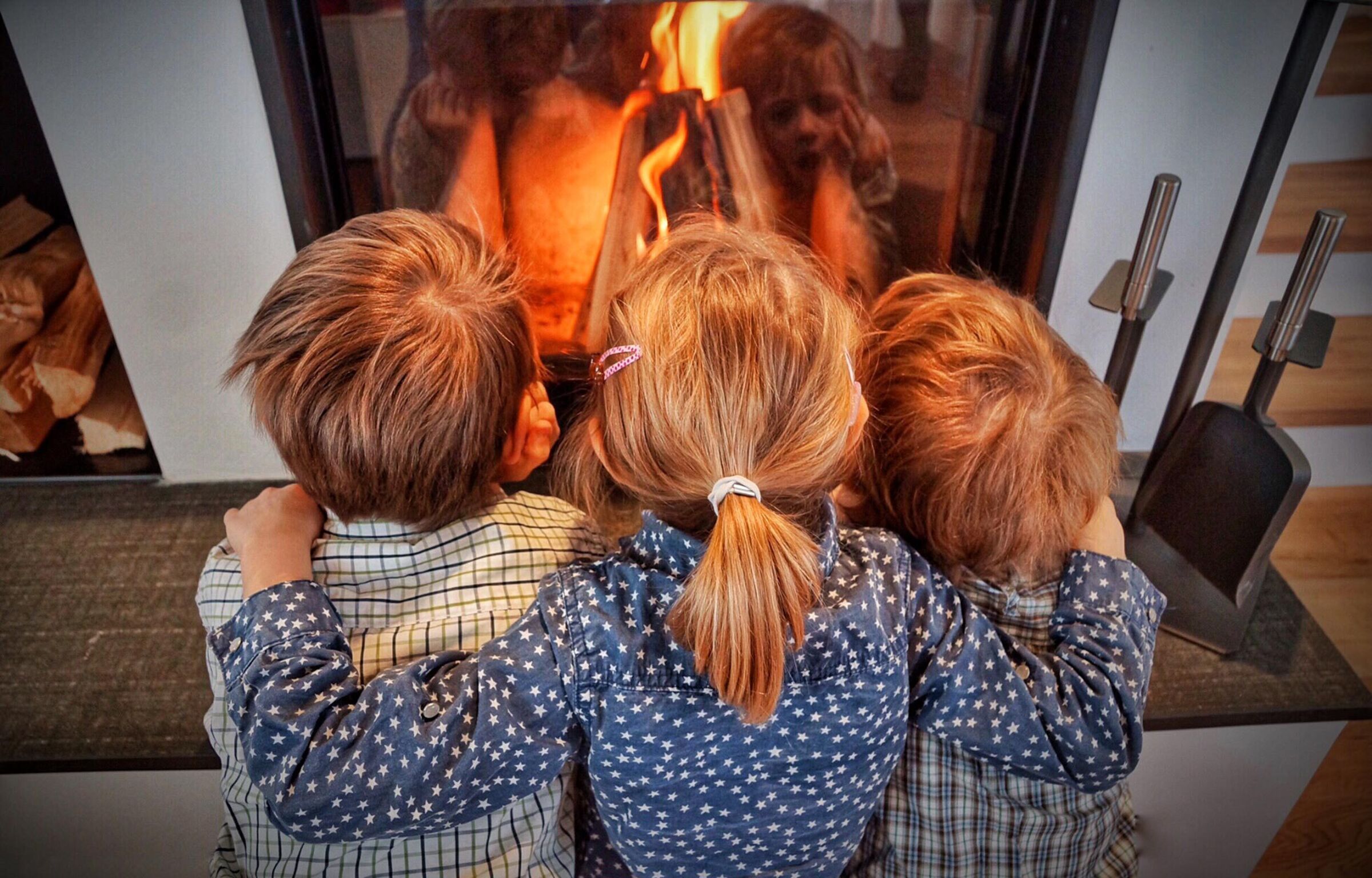 Three children sitting in front of the fireplace in a chalet in Carinthia