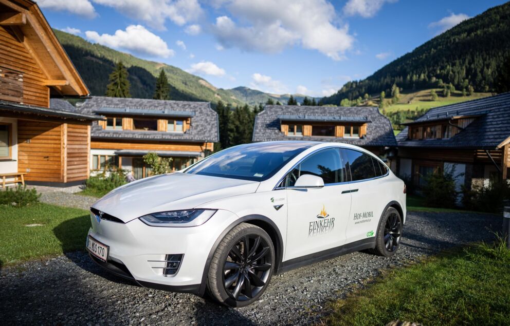 A Trattlerhof Tesla car stands in front of the chalets in Carinthia