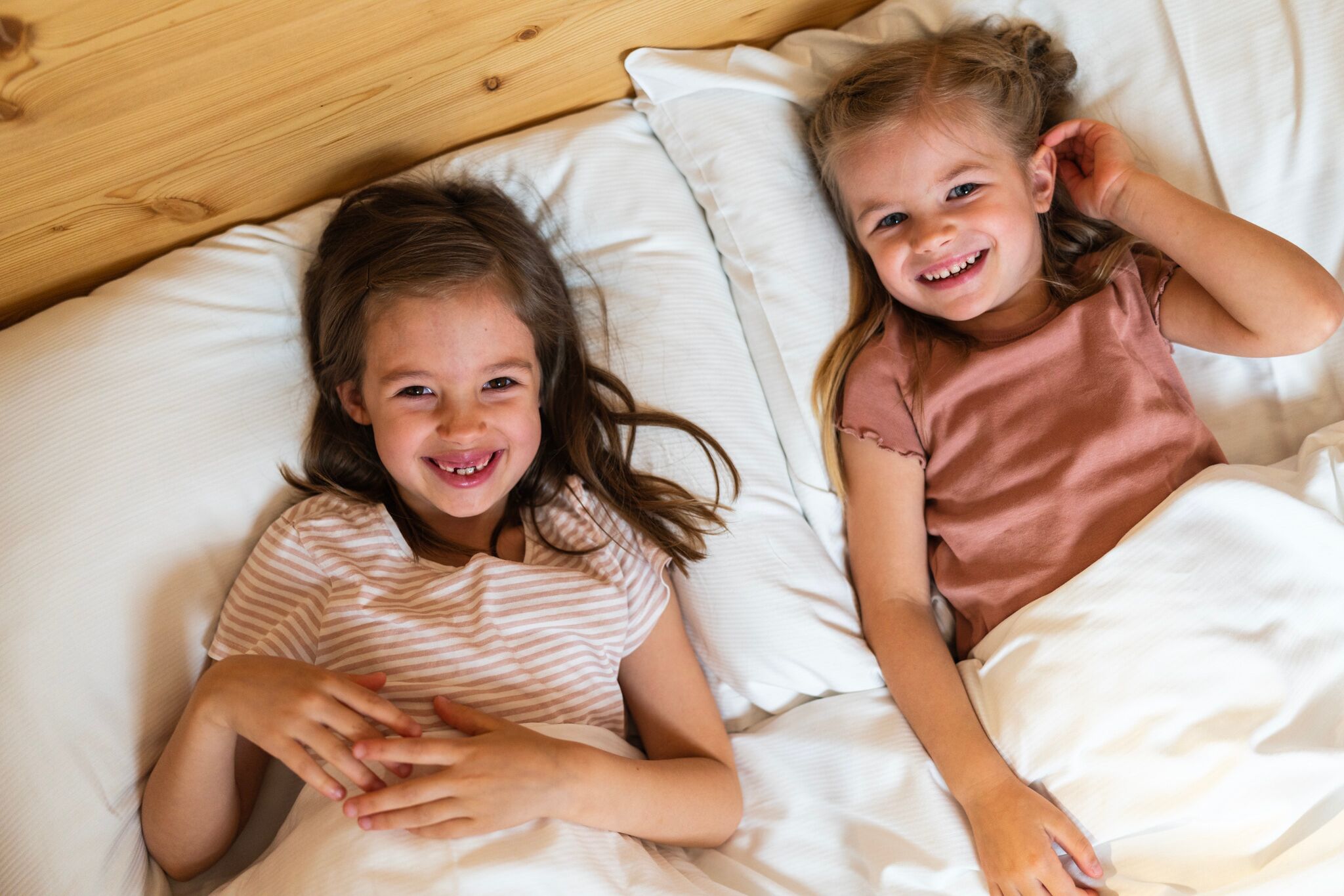 Zwei Mädchen die im Bett von einen Zimmer von Trattlers Hof-Chalets liegen.