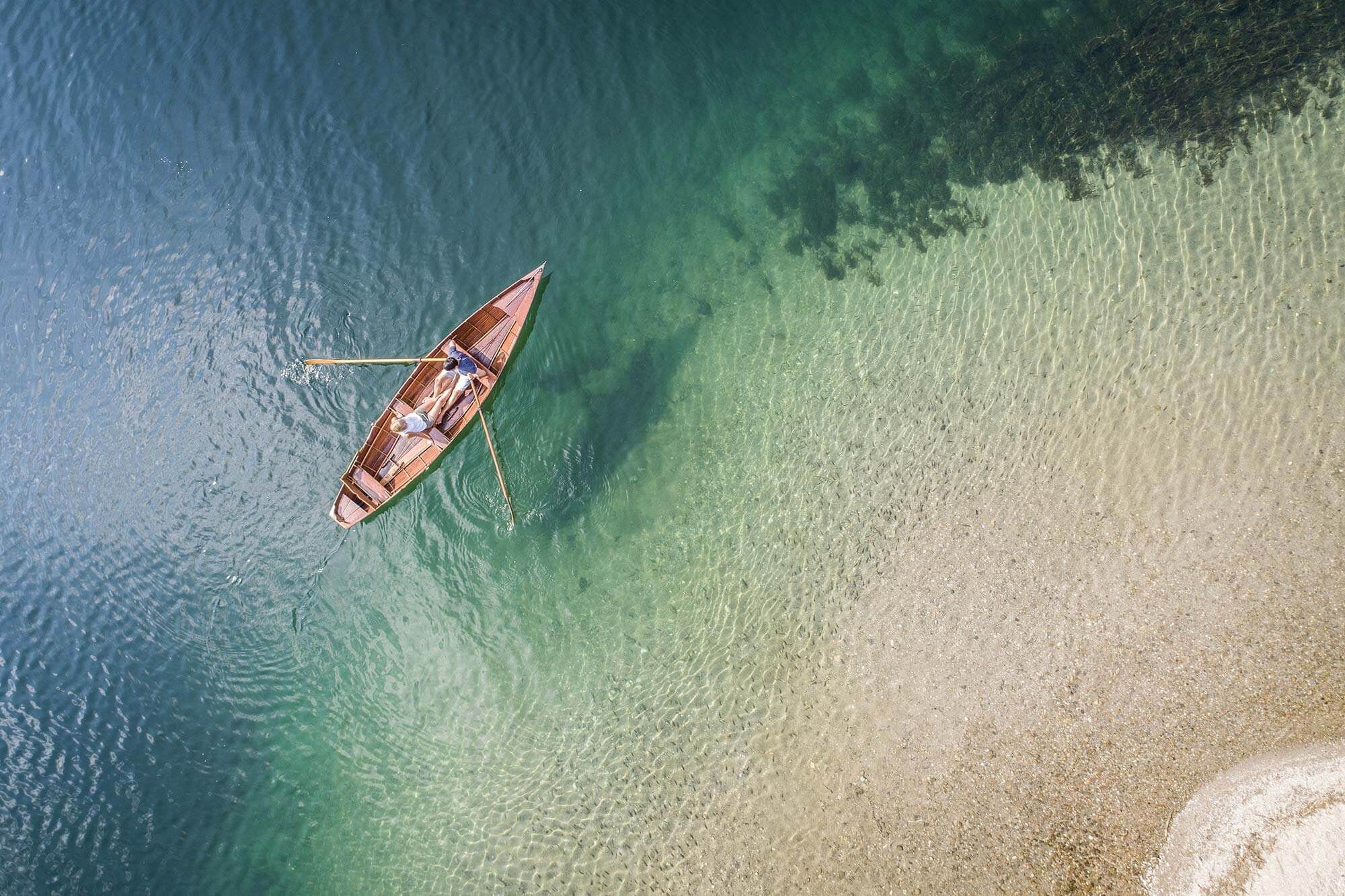 Una barca galleggia sull'acqua blu accanto a una spiaggia sabbiosa