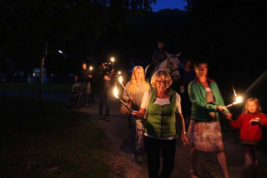 Viele Menschen gehen bei Nacht mit Fackeln und Pferden in Kärnten Wandern