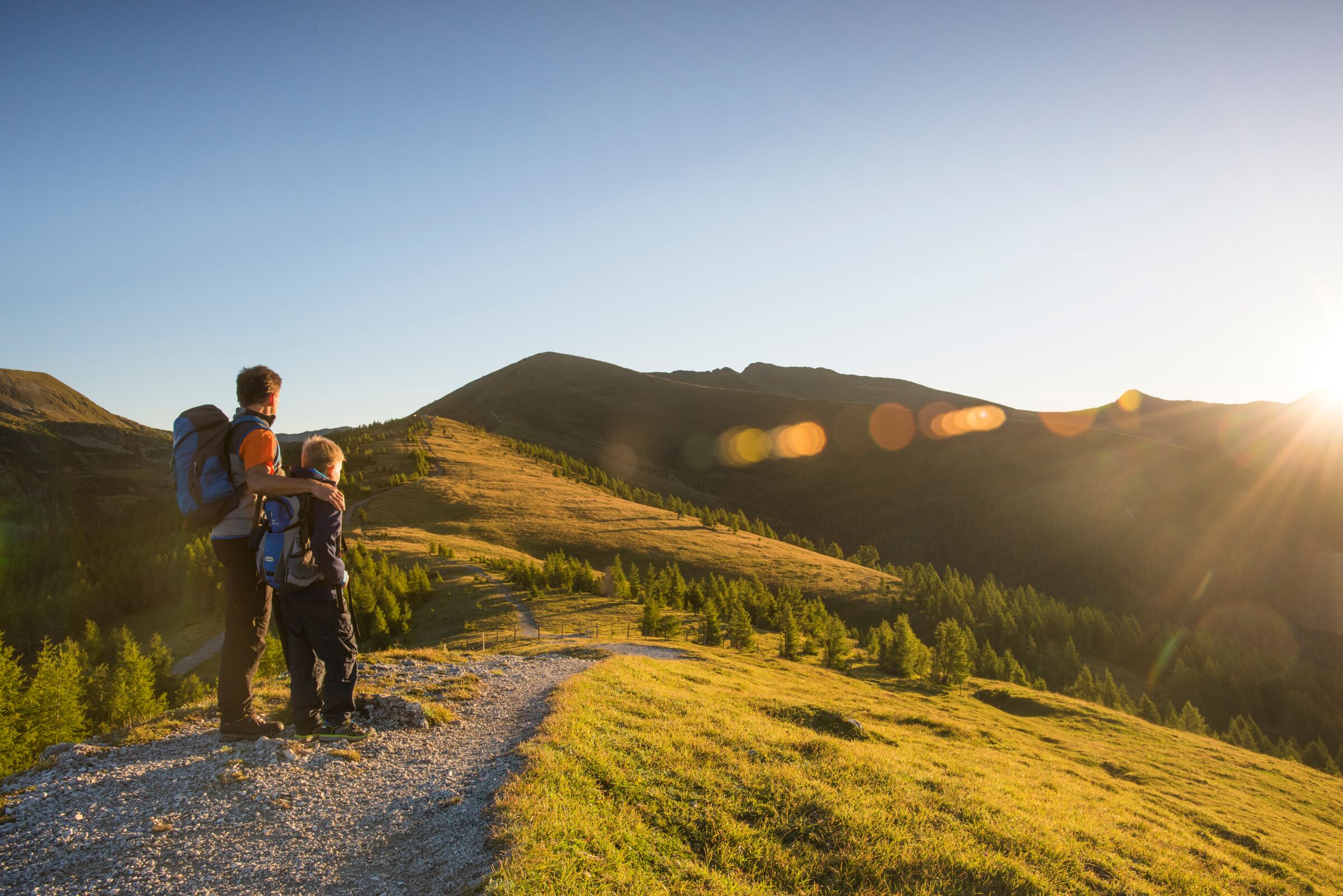 Padre e figlio passeggiano tra le splendide montagne e guardano il sole.