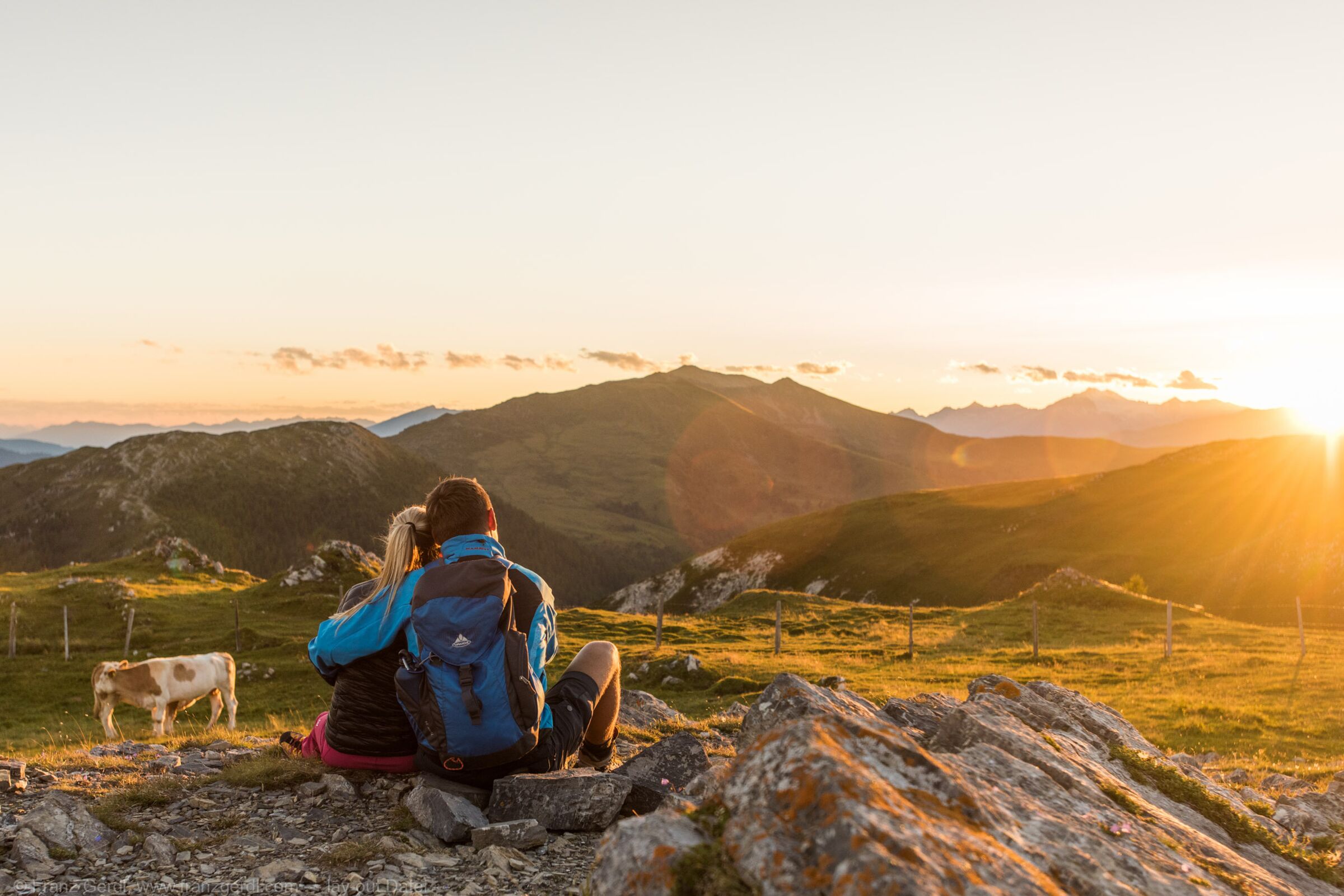 A couple watches the sunrise while hiking in Carinthia