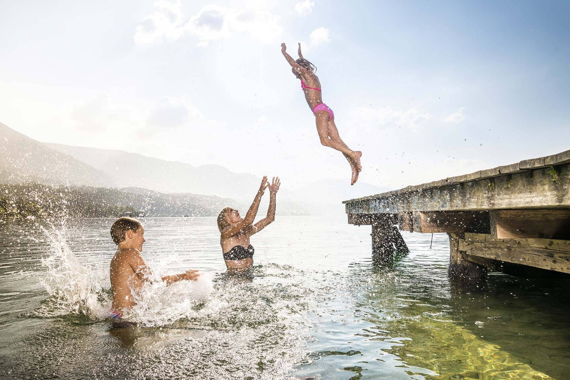 Child jumps from a jetty into the lake where the mother wants to catch her.