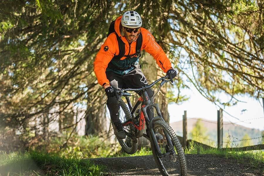 Ein Mountainbiker fährt bei schönem Wetter im Wald den Flow Country Trail in Kärnten