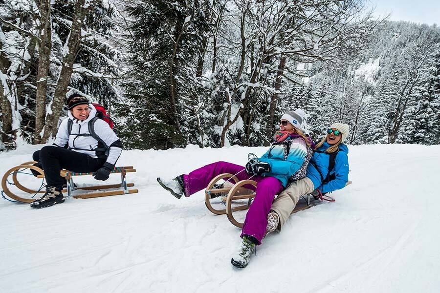 Drei Frauen fahren am einen Wintertag die Rodelbahn in Bad Kleinkirchheim herunter