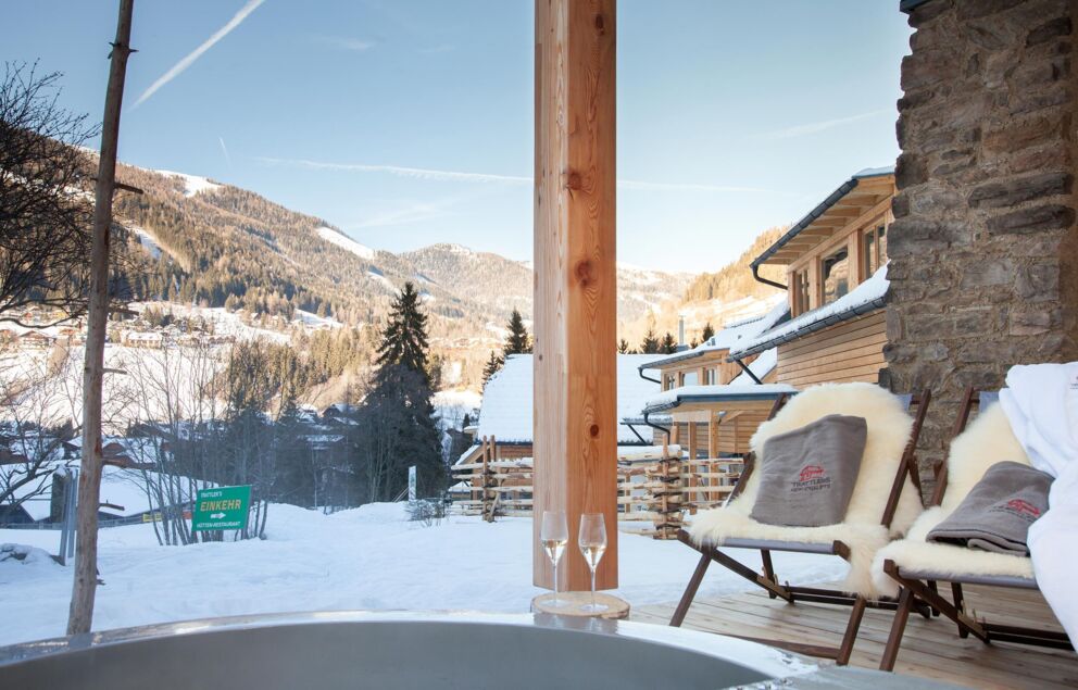 Eine beheizte Außenwanne mit bequemen Stühlen mit Blick auf die schneebedeckten Berge.