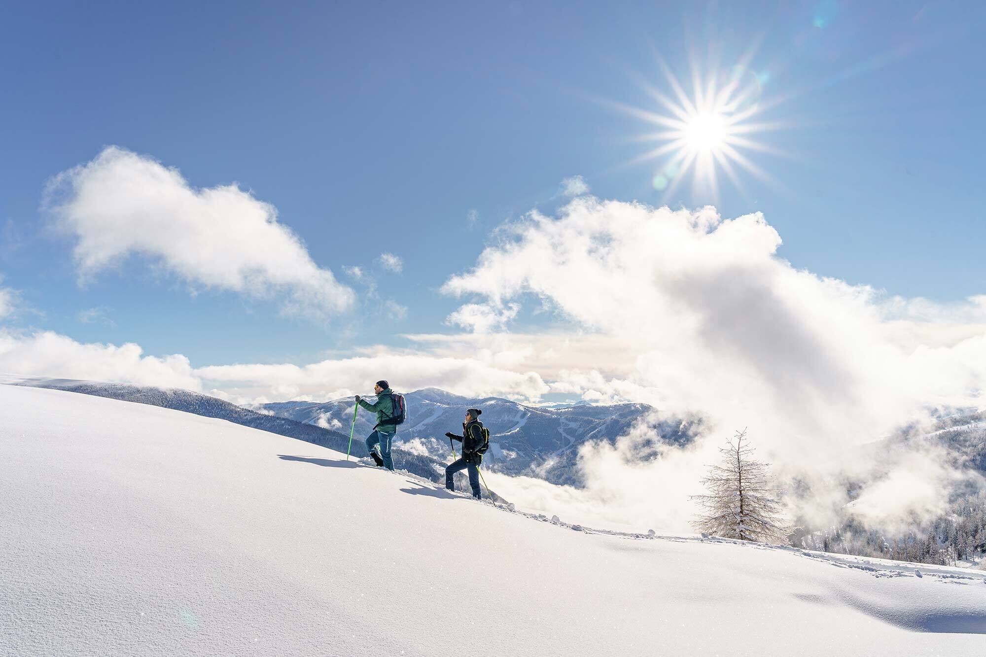Due persone che ciaspolano nella neve alta in Carinzia.