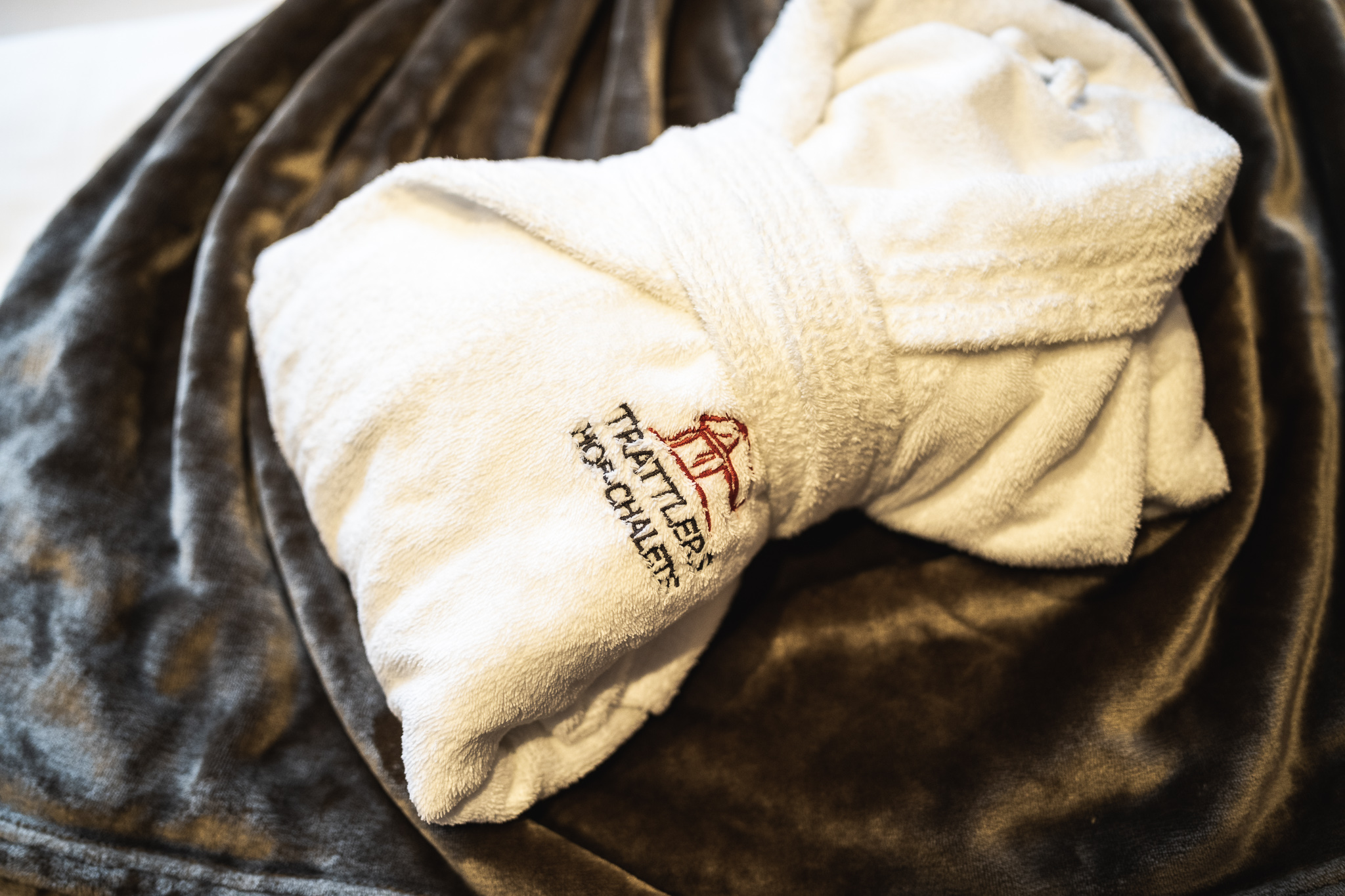 A white bathrobe with the logo of Trattlers Hof-Chalets on it.