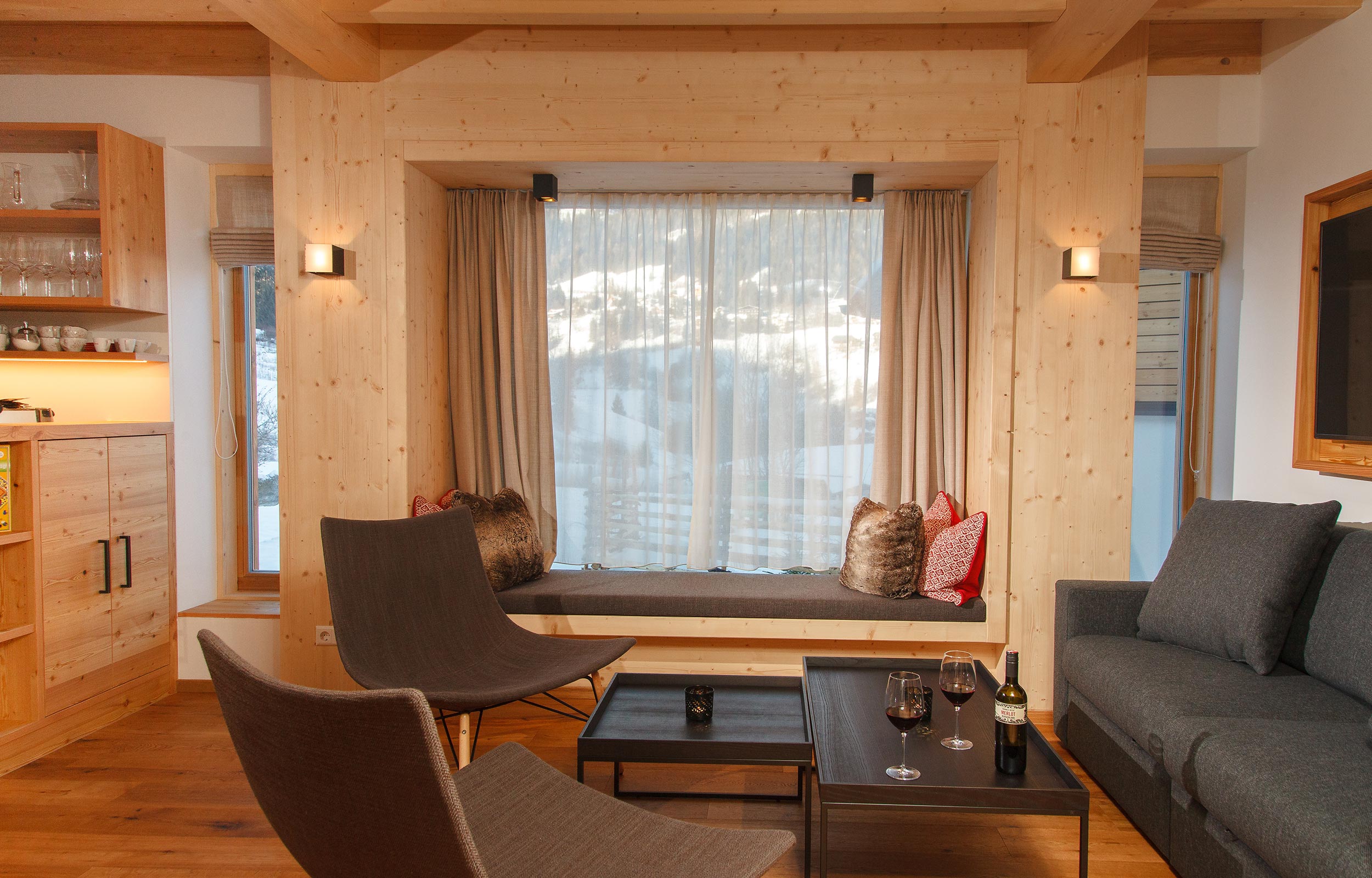 Wohnzimmer mit dunkeln Sofa und Panoramafenster in Kärnten